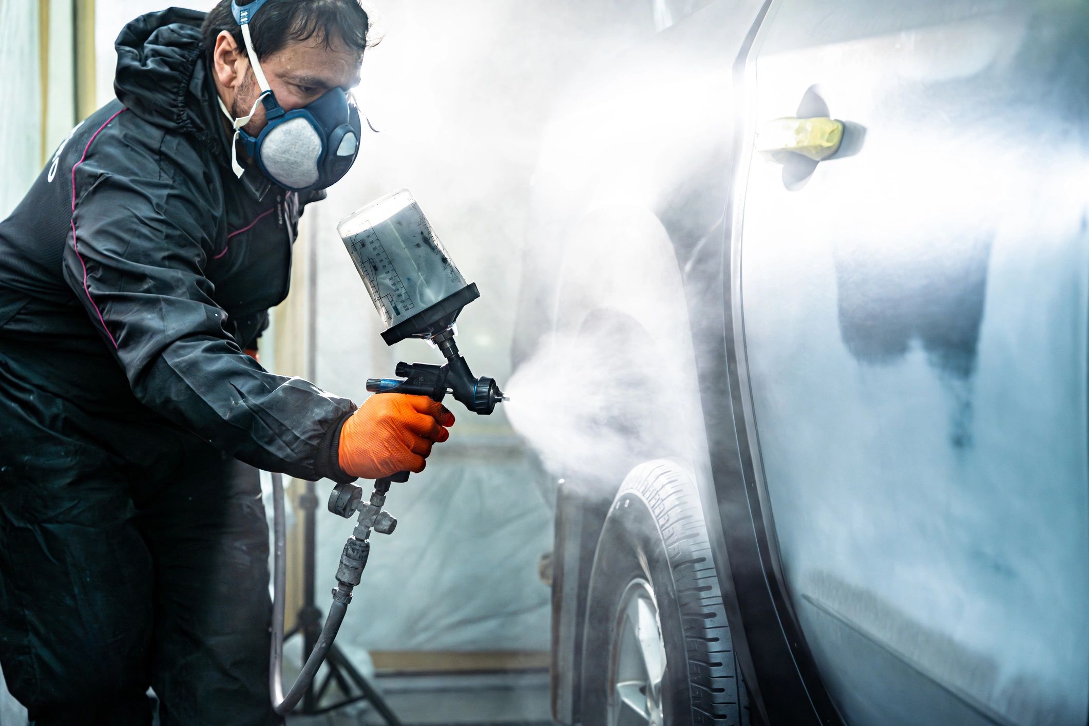 Auto body painter spraying paint in a professional booth